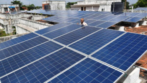 Solar panels installation on rooftop by professional wearing safety gear.