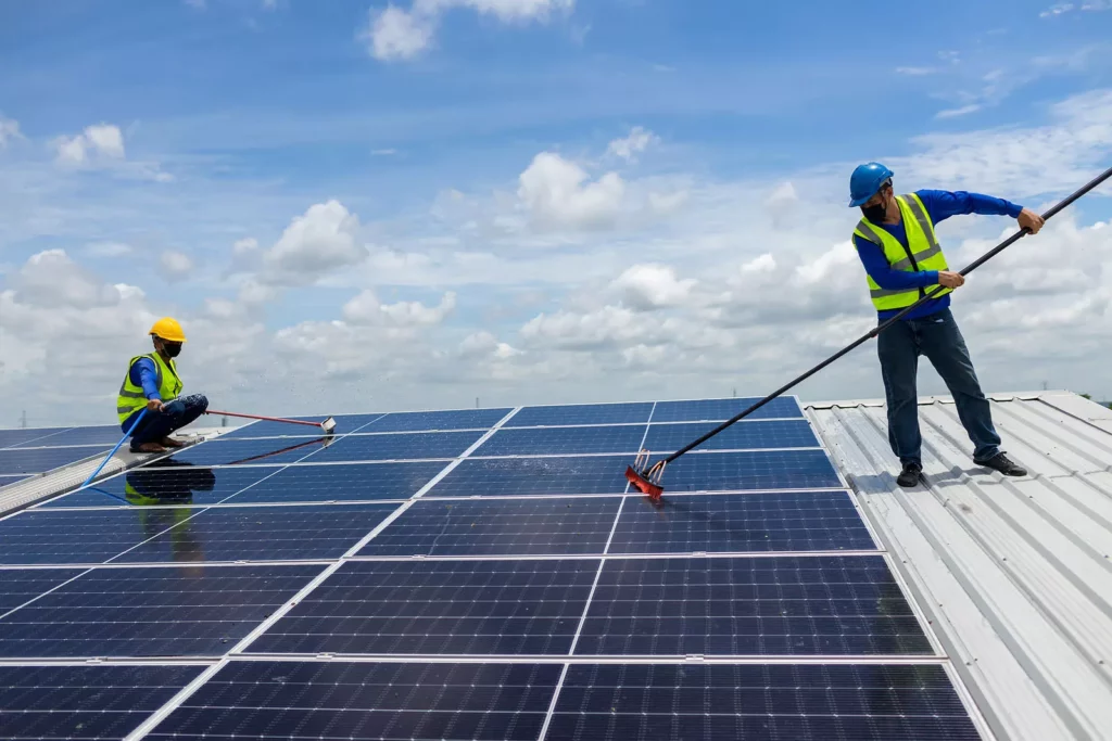 Two men cleaning solar panels on a roof, ensuring optimal efficiency and energy production